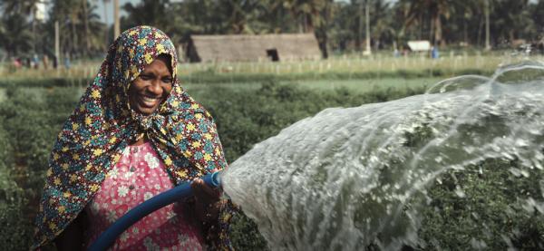 Smiling woman spraying water from a hose
